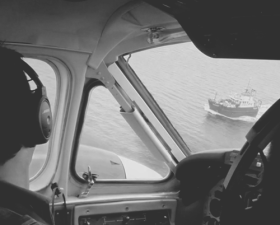 A pilot looking out the window of maritime patrol aircraft