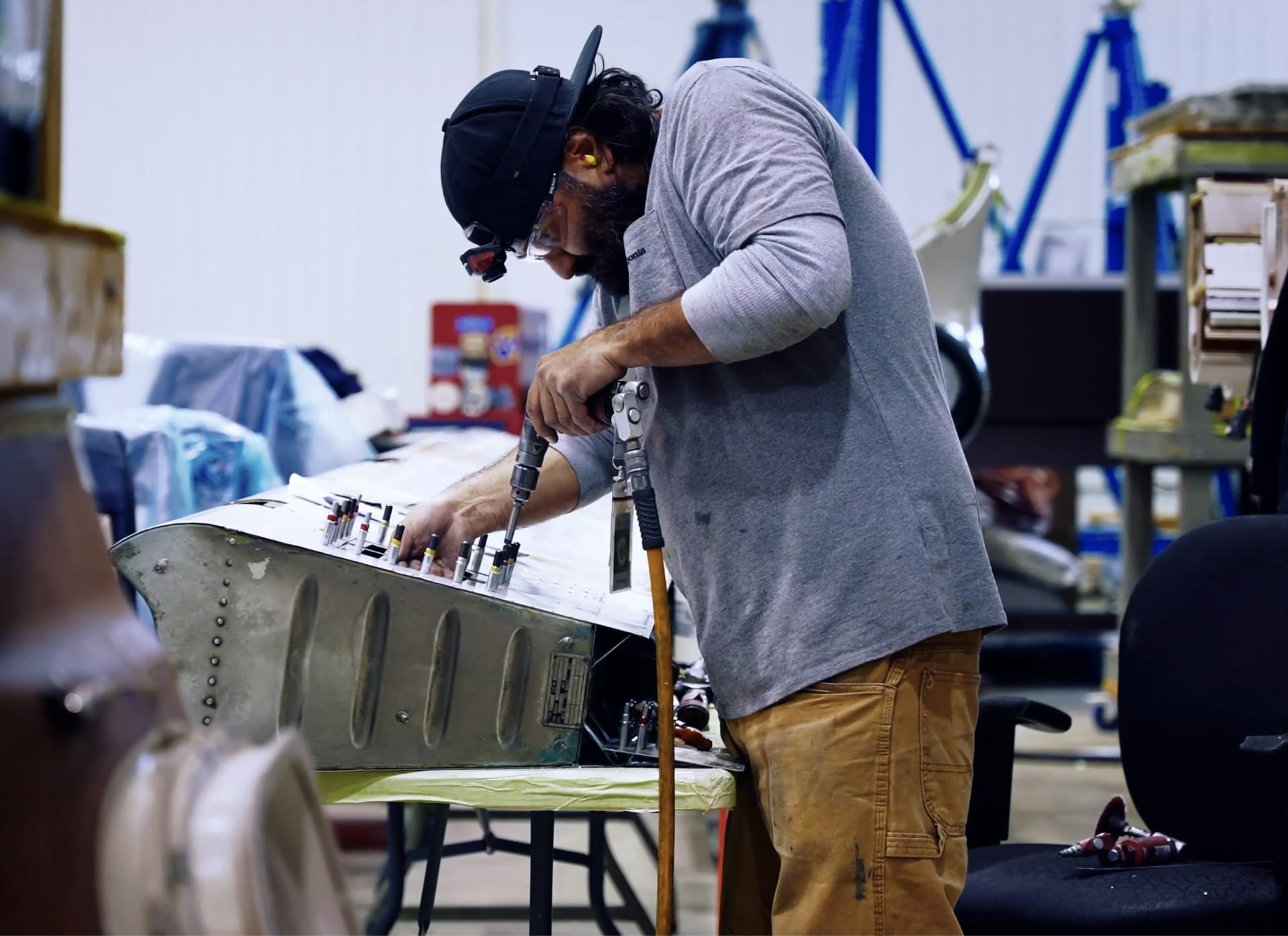 Aircraft maintenance engineer using power tool on airframe in hangar