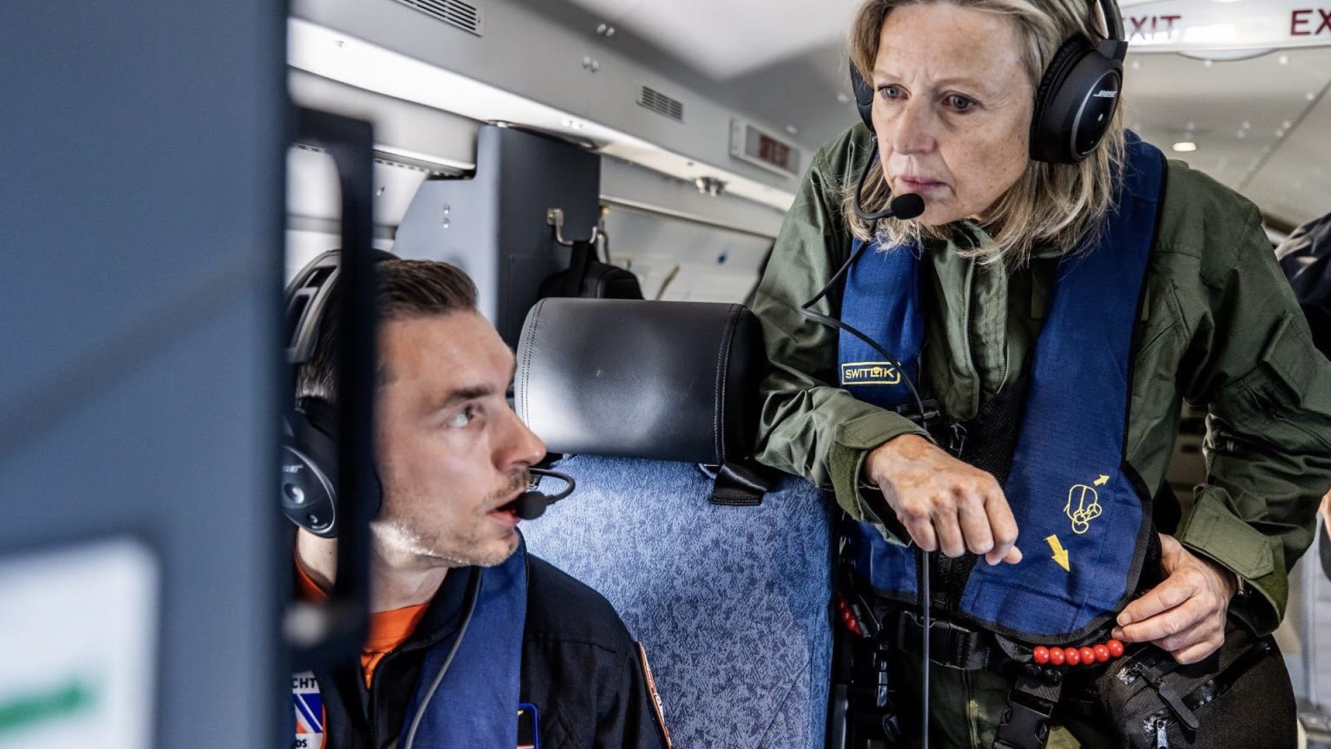 Image of 2 aircraft operator on an aircraft discussing their mission