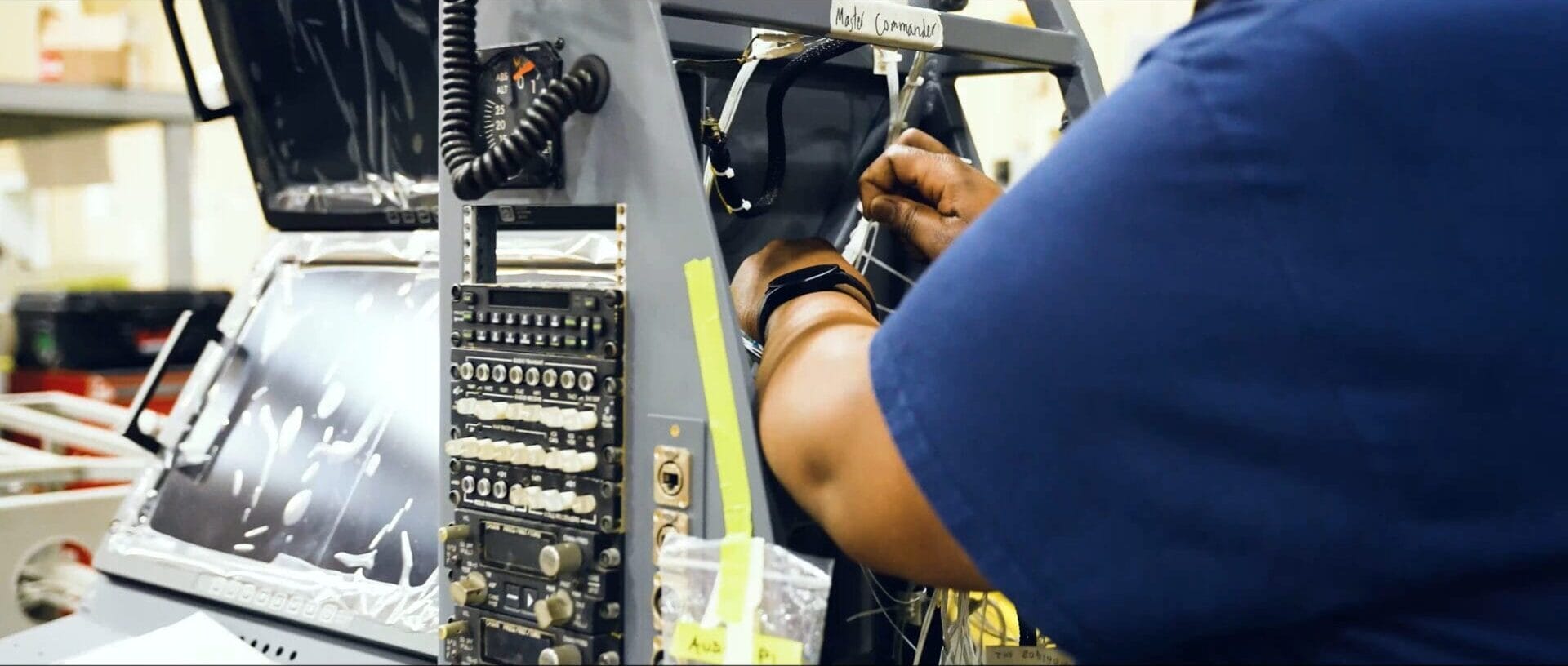 AME working on electrical components in mission console in hangar