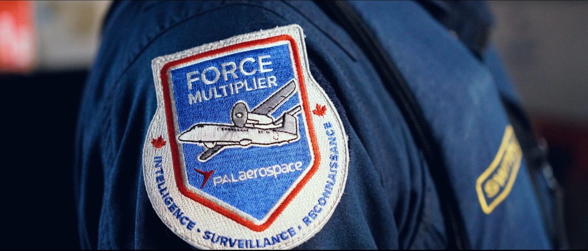 PAL Aerospace Force Multiplier lennumärk tumesinist lennukombinesooni kandva piloodi paremal õlal