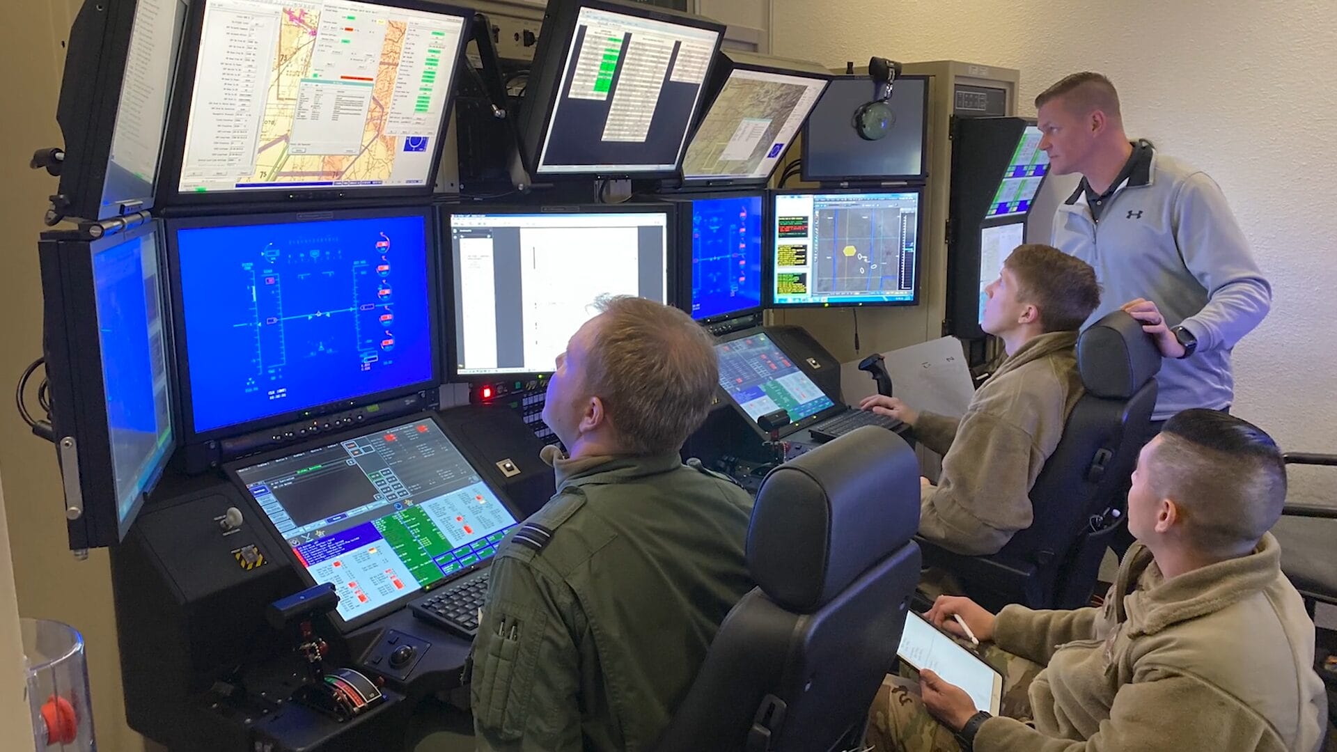 Photograph of a training session with 2 students and 2 instructors at the training consoles